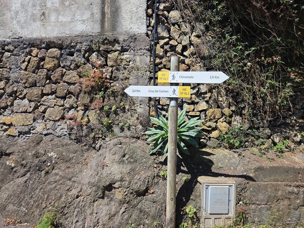Signpost at a stone wall indicating the PR TF-10.1 connection and directions to Chinamada and Cruz del Carmen.