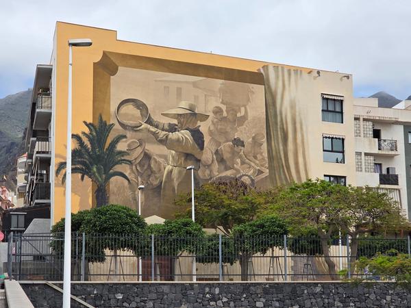 Large mural showing traditional Canarian workers on the side of a residential building.