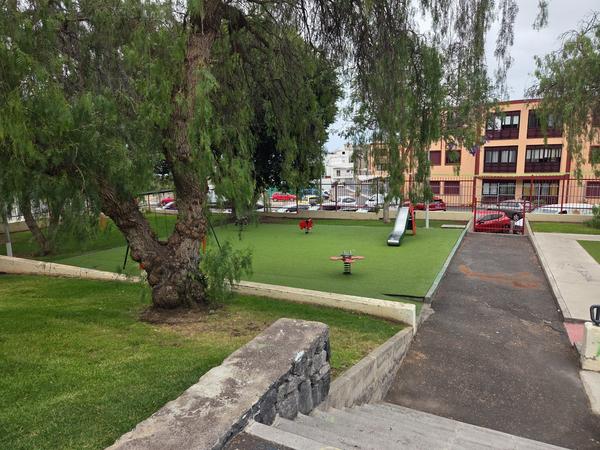 Children's play area with grass surface and trees inside Parque Santa Ursula in Adeje.