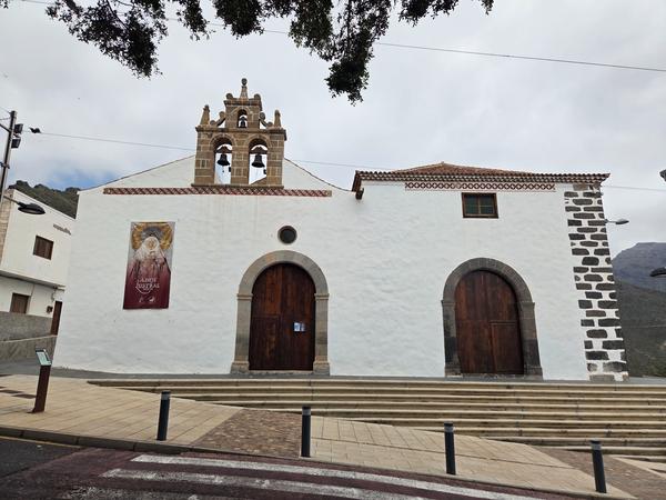 View of Parroquia de Santa Ursula with triple bell tower and whitewashed facade.