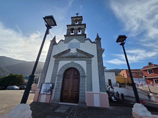 Fachada principal de la iglesia de Aguamansa con campanario y plaza infantil al lado.