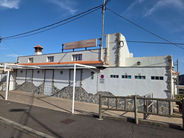 Fachada del Restaurante Cruz de Tej con muros blancos y piedra, abierto desde 1957 en la carretera principal.