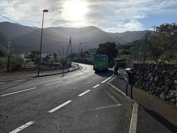 Guagua de la línea 345 circulando por la carretera de Aguamansa con montes al fondo.