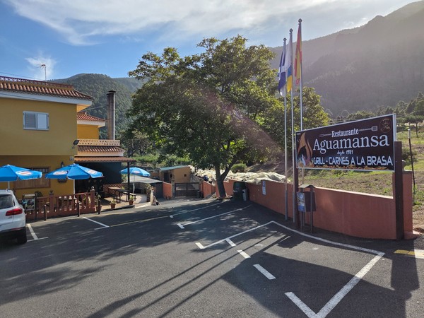 Entrada del Restaurante Aguamansa con terraza y banderas, especializado en carnes a la brasa desde 1981.