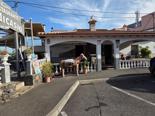 Fachada con terraza del restaurante Casa Nicasio y decoración rústica frente al estacionamiento.