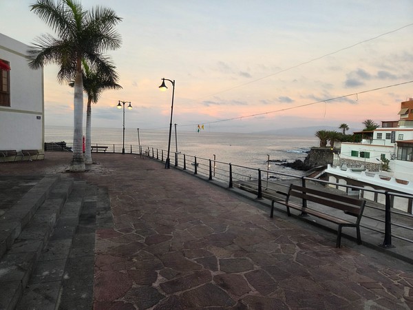 White seafront terraces and steps at the Alcalá muelle with houses climbing the slope behind.