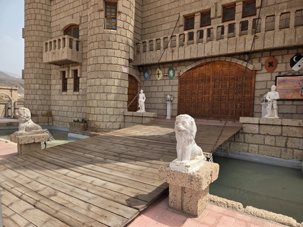 Close view of the drawbridge, lions and heavy wooden gates of Castillo San Miguel in Aldea Blanca.