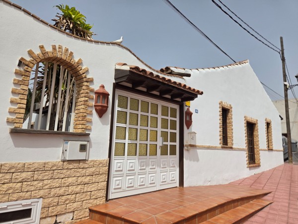 Traditional single-storey house in Aldea Blanca with arched window, brick trim and tiled steps.