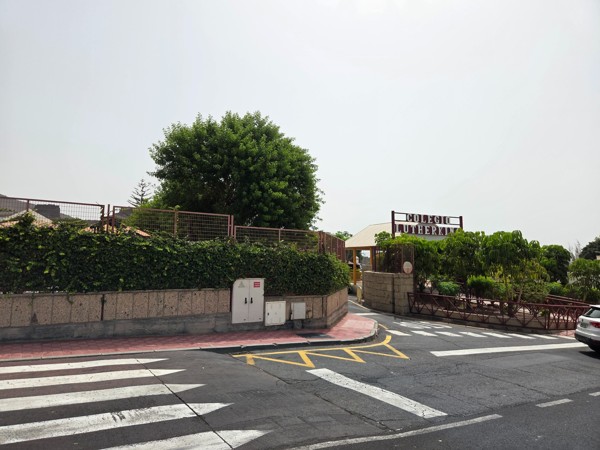 Entrance area and signage of Colegio Luther King near Aldea Blanca with greenery along the fence.