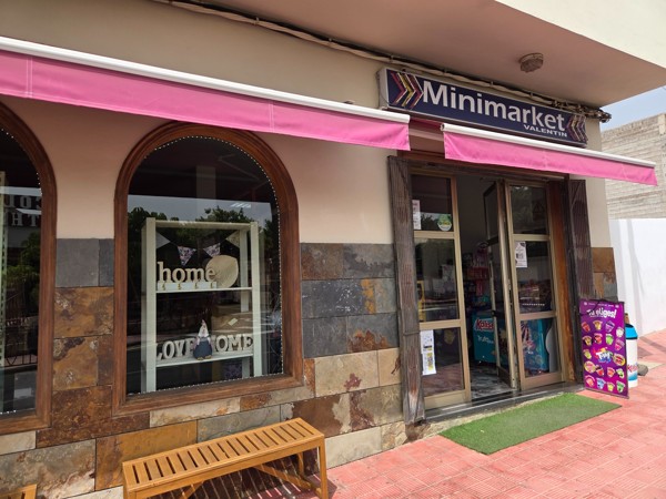 Entrance of Minimarket Valentín in Aldea Blanca with pink awning and display signs.