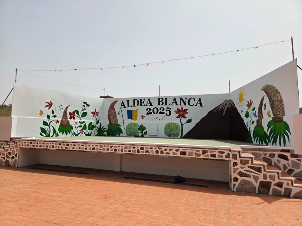 Colorful mural stage in the plaza of Aldea Blanca with flowers, Mount Teide outline and the Canary Islands flag, marked 2025.