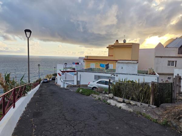 Steep street in Almáciga leading down to the sea with houses and clotheslines.