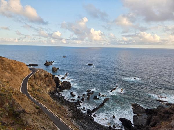 Coastal overview of Almáciga, Tenerife, with white houses and dramatic cliffs at sunset.