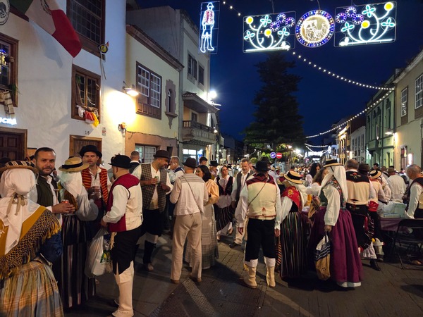 Groups chatting beneath festive lighting in a historic street of La Laguna during the San Benito Abad celebrations.