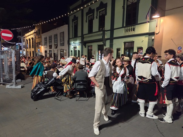 Group of young people in striped skirts and vests chatting in a street of the historic centre during the celebration.