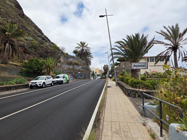 Entrance road into Bajamar with the town sign and palm-lined sidewalk.