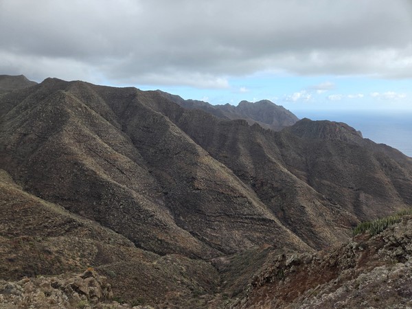 Panoramic view of multiple rugged mountain ridges near Barranco de Zapata under a cloudy sky.