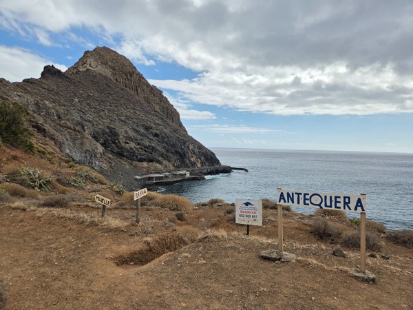 Panoramic view of Playa de Antequera with the steep volcanic headland, small pier and Atlantic Ocean at the mouth of Barranco de Antequera.