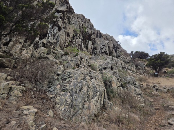 Jagged volcanic rock wall rising above the hiking trail in the upper section of Barranco de Antequera.