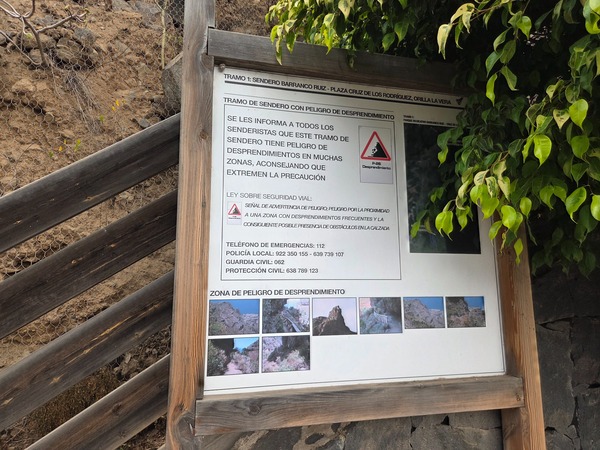 Close-up of the official notice warning about landslide risk along the Barranco Ruiz trail, with emergency phone numbers.