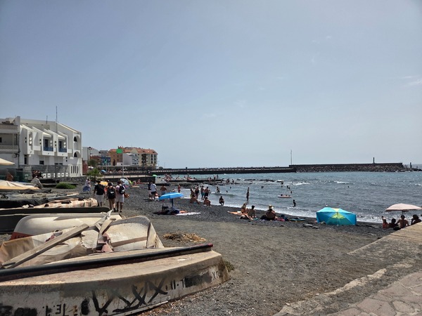 Small fishing boats pulled onto the gravel near a family beach in El Puertito de Güímar.