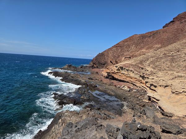 Volcanic cliffs meeting the Atlantic Ocean with waves crashing on the dark rocky shore in Tenerife.