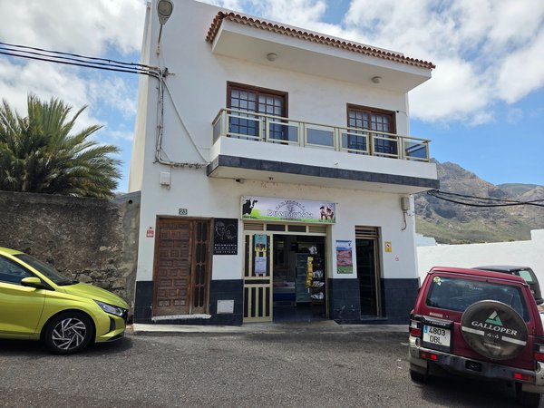 Entrance to a local butcher shop called 'Carnicería Buenavista' with mountain backdrop.