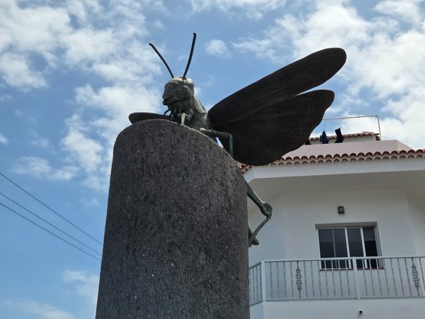 Large metallic insect sculpture on a concrete pedestal in Buenavista.