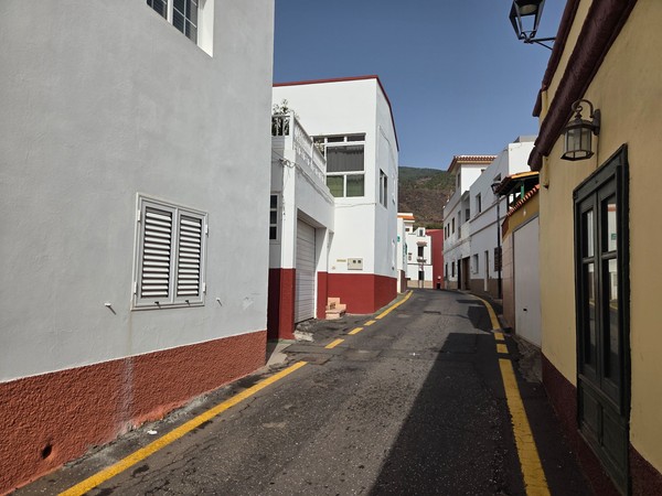 Quiet narrow street in Barranco Hondo with white façades, shutters and yellow curb lines.