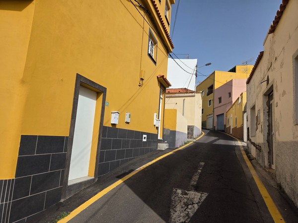 Close view of mustard-yellow house and traditional façades lining a narrow lane in Barranco Hondo.