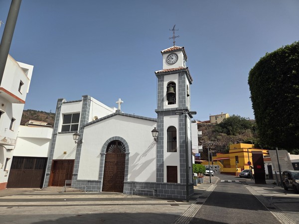 Small parish church in Barranco Hondo with a clock and bell tower on the square.