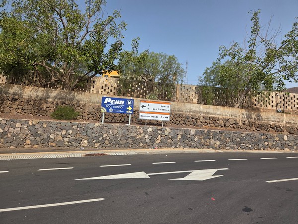 Road sign at a Barranco Hondo junction pointing toward Igueste and Las Caletillas; a nearby fuel station sign helps identify the turn.