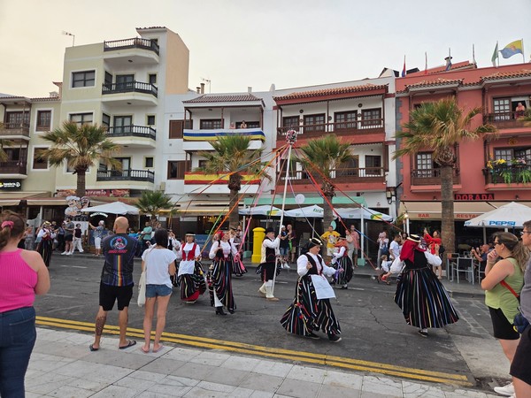 Folk dancers in traditional costumes performing a ribbon dance in front of cafés in Candelaria.
