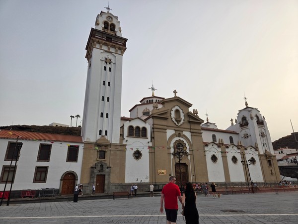 Full façade and bell tower of the Basilica of Our Lady of Candelaria with fiesta decorations.