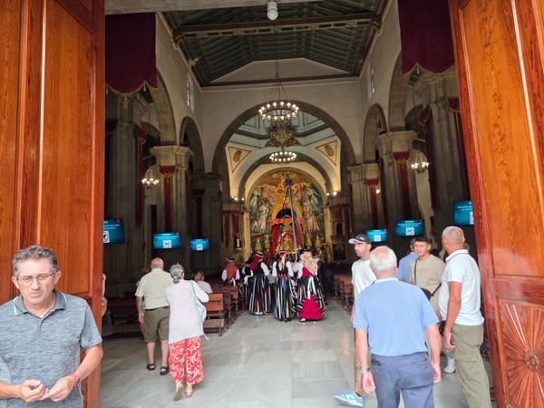 Interior of the Basilica of Candelaria with worshippers and folk costumes near the sanctuary.