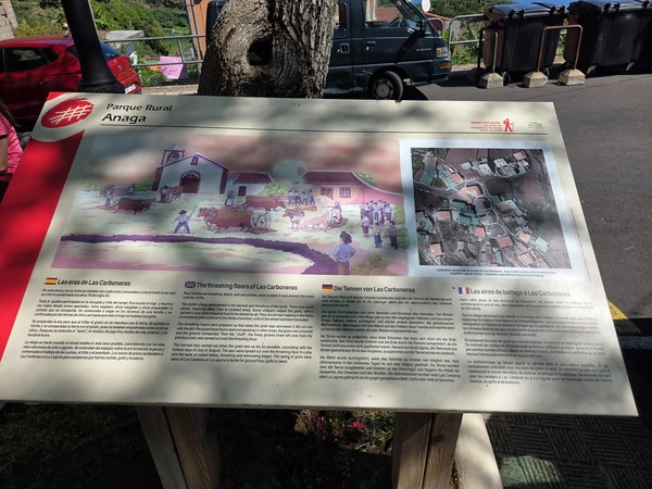 Informational board at the village plaza explaining the history of the traditional threshing floor.
