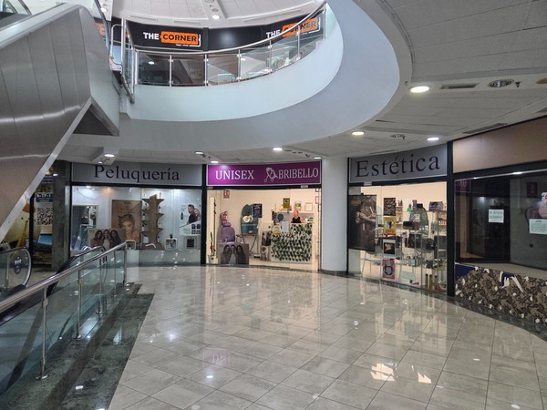 Row of beauty and hairdressing storefronts including Peluquería and Estética on the lower level corridor.