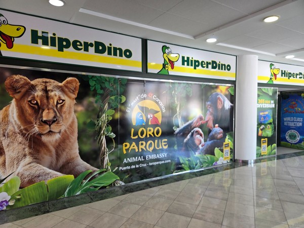 HiperDino signage along the corridor with a colorful promotional wall and directions to the store.