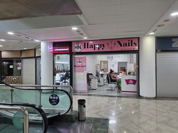 Happy Nails salon interior where technicians work with clients near the escalators.