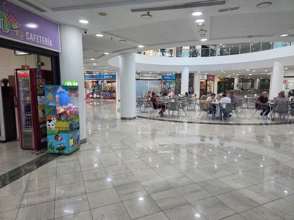 Central dining area with many tables where visitors sit and eat inside the shopping center.
