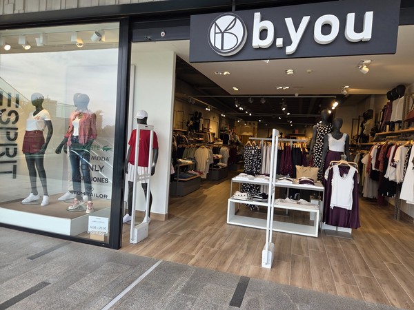 b.you window with mannequins and neatly arranged racks inside.