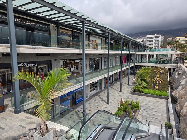 Multi-level interior of Rosa Center with escalators, glass railings and planted areas.