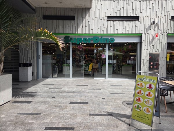 SuperDino supermarket entrance with trolleys and promotional signs.