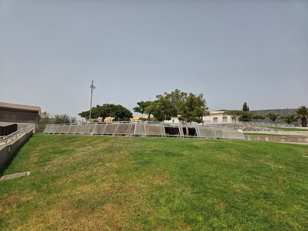 Grassy green zone with solar panels and trees near the center of La Chafira.