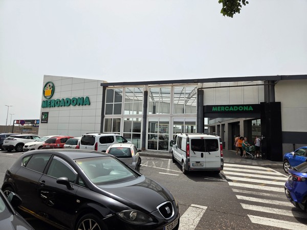 Modern Mercadona supermarket entrance with shoppers and parking area.