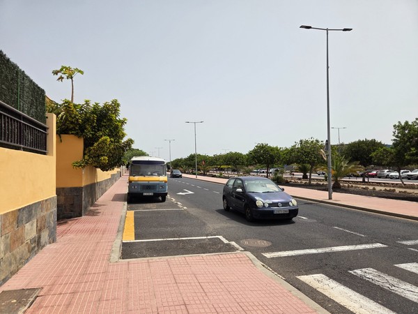 Main road with bus stop, trees, and traffic near La Chafira.