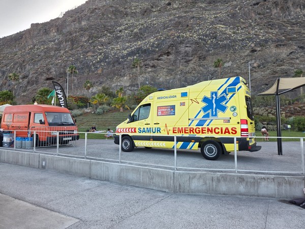 Yellow emergency ambulance parked beside the promenade during an event at Los Charcos de Valleseco.