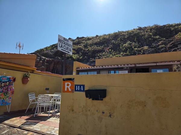 Bar Restaurante La Cueva with its yellow walls and outdoor tables, offering refreshments to hikers in Chinamada.
