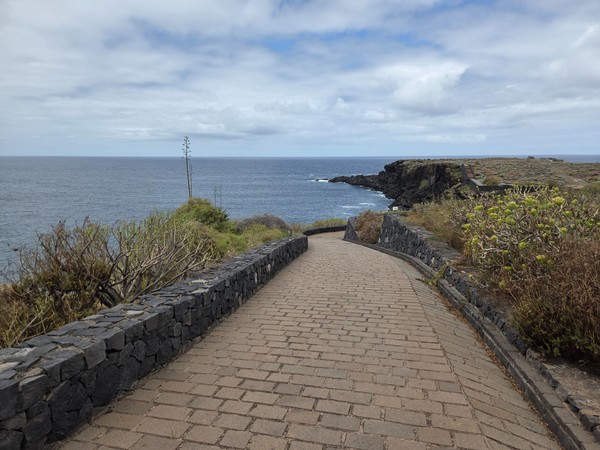 Stone-paved coastal path curving toward a headland above the Atlantic on the Costa de Acentejo.
