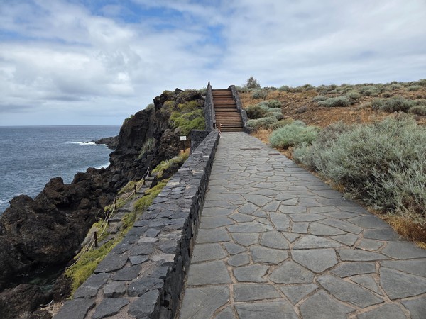 Wide stone path leading to wooden stairs on the cliff edge at the protected coastline of Acentejo.